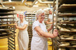 © Robert Kneschke - Baker team pushes tray trolley with fresh baked goods