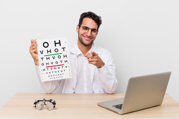 hispanic handsome man pointing at camera choosing you. optical vision test concept