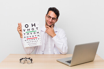 Poster - hispanic handsome man smiling with a happy, confident expression with hand on chin. optical vision test concept