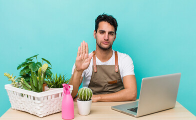 Poster - hispanic handsome man looking serious showing open palm making stop gesture. garden and plants concept