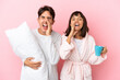 © luismolinero - Young couple in pajamas isolated on pink background shouting and announcing something