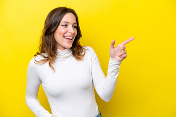 Sticker - Young caucasian woman isolated on yellow background pointing finger to the side and presenting a product