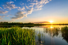 Amazing View At Scenic Landscape On A Beautiful Lake And Colorful Sunset With Reflection On Water Surface Among Green Reeds And Glow On A Background, Spring Season Landscape