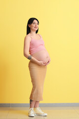 Wall Mural - Pregnant young woman on yellow background