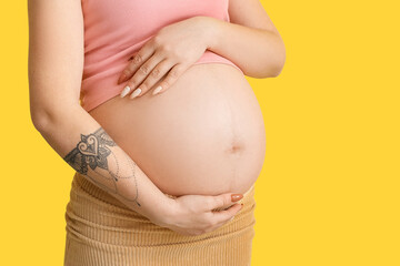 Wall Mural - Pregnant young woman on yellow background