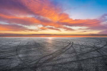 Empty asphalt road and lake with sky sunset clouds background