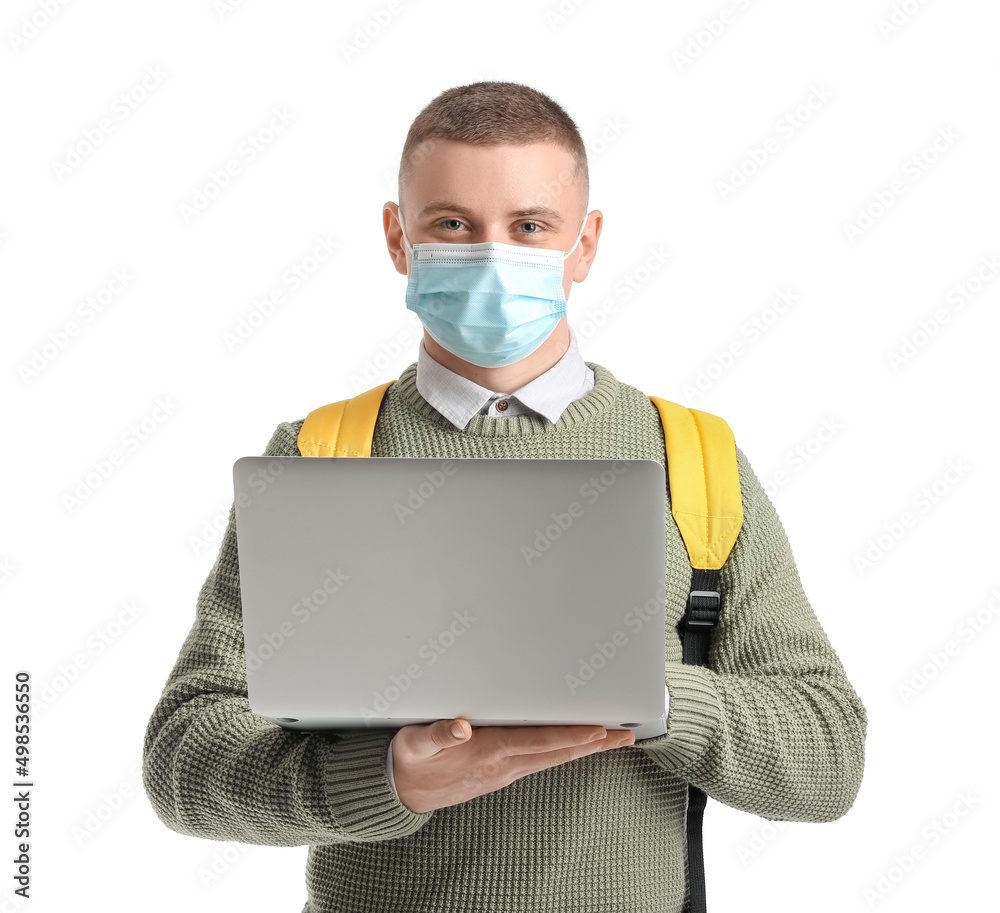 Male student in medical mask using laptop on white background