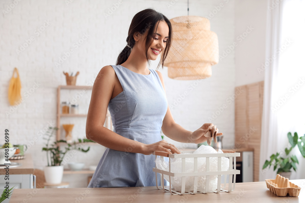 Young woman sorting garbage in kitchen