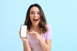 © Pixel-Shot - Excited young woman with mobile phone on blue background