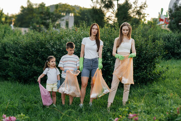 A group of adults and children together at sunset is engaged in garbage collection in the park. Environmental care, waste recycling. Sorting garbage.