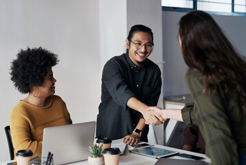 Poster - Its been a pleasure doing business with you. Cropped shot of a group of young businesspeople greeting each other with a handshake before sitting down in the office.