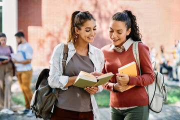 Wall Mural - Happy female students read from book together at campus.