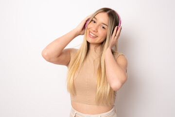 Wall Mural - Smiling pretty young woman wearing headphones listening music isolated over white background