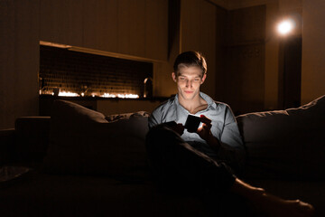 Young man with mobile phone at night. The user of the gadget creates a social network. Communication in the night chat. Internet addiction.