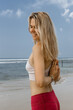 © Nastassia - Vertical photo of Young yogi woman practicing yoga, standing in sea with Namaste behind the back, working out wearing black swimsuit.