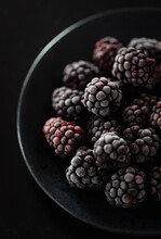 Close Up Of A Black Bowl Of Frosty Frozen Blackberries.