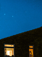 Shot of two windows of a house under evening starry blue sky