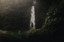 Man Admires The Beauty Of A Waterfall In The Forest On A Foggy Day