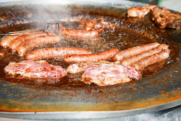 Poster - Closeup shot of sausages and meat preparing in a pan