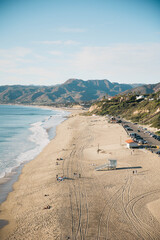 Sticker - Aerial view of Zuma Beach and mountains against blue sky on a sunny day in Malibu, California, USA