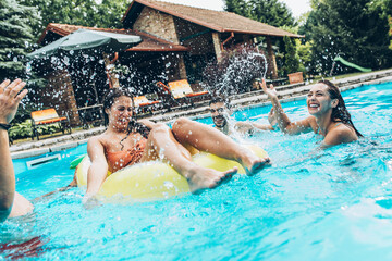 Wall Mural - Friends are having fun and playing in the swimming pool.They are smiling and joying on a hot summer day.	
