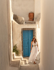 Wall Mural - Young beautiful pretty white woman in Oil old town in Santorini greek island in Greece near blue door and white buildings in summer. High quality photo