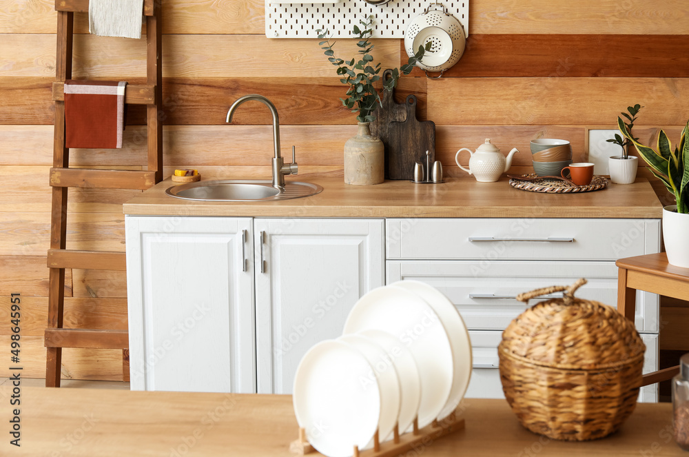 Plates on table and kitchen counter with sink near wooden wall