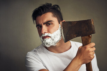 Poster - Its the right tool for the job. Shot of a handsome young man shaving his beard with a lumberjack.