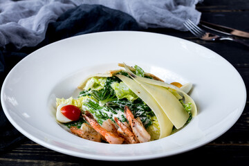 Sticker - salad caesar with shrimps on white plate on black wooden table