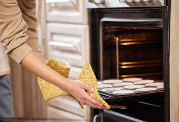 Poster - In 30 minutes Ill have cups of yumminess. Shot of a woman inserting a tray of cupcakes into the oven to bake.