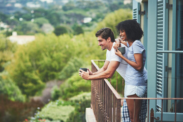 Sticker - This place is simply amazing. Shot of an affectionate young couple drinking coffee and looking at the view while standing on a balcony at home.