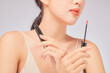 © Tuan  Nguyen  - Front view of model using lipstick in white background for cosmetic advertising