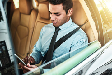 Poster - Hes got all his tasks saved on one handy device. Shot of a young businessman using a digital tablet while sitting in the back seat of a car.