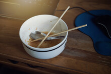 Work From Home. Low Key Image Of Short Spoon And Chopsticks In Bowl Ceramic Of Finished Eating Instant Noodles After Working In Front Of Notebook Computer With Urgent.