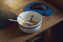 Work From Home. Low Key Image Of Short Spoon And Chopsticks In Bowl Ceramic Of Finished Eating Instant Noodles After Working In Front Of Notebook Computer With Urgent.