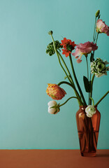 Wall Mural - Vertical still life composition of flower bouquet in brown glass vase against light bluish green wall background