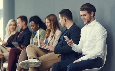 Poster - The queue to success. Shot of a group of businesspeople using different wireless devices while waiting in line for an interview.