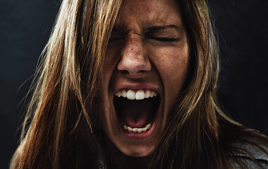 shes reached the end of her rope. a young woman screaming uncontrollably while isolated on a black b
