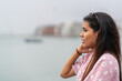 Portrait of a young latina woman gazing the horizon next to a harbour