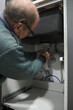 Mature plumber installing sink siphon in domestic kitchen. Repairman working.