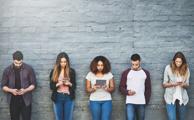 Aufkleber - Meet generation Y. Shot of a group of young people using their wireless devices together outdoors.