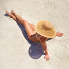 Wall Mural - Sea, sun and summer fun. High angle shot of a young woman relaxing at the beach.