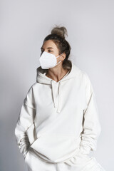Wall Mural - Young woman wearing white hoodie and ffp2 respirator mask