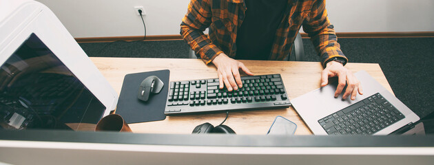 The guy in office working with the laptop and pc in the same time