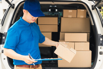 Wall Mural - Asian young delivery man courier in uniform hold documents clipboard checking list parcel post boxes near a car for service shipment to customer, Online shopping service concepts