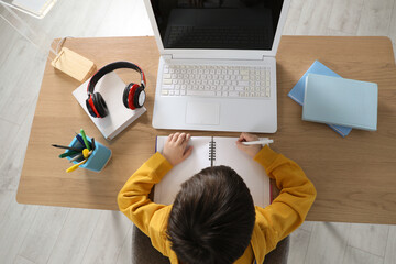 Wall Mural - Cute little boy with modern laptop studying online at home, top view. E-learning