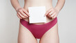 woman in panties holding empty sign with copy space over belly as women's health or gynecological disorder concept