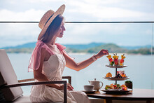 Afternoon Tea In Luxury Restaurant With Sea View. Elegant Woman Eating Slices Fresh Fruits In Cafe From Stand With Sweets Delicious Cakes And Sandwiches. High Tea Selection, Romantic Dinner