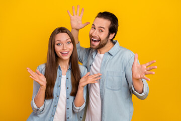 Wall Mural - Photo of shocked charming husband wife wear jeans shirts rising hands arms isolated yellow color background