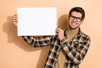 portrait of attractive cheerful guy holding in hands demonstrating copy empty space banner isolated 